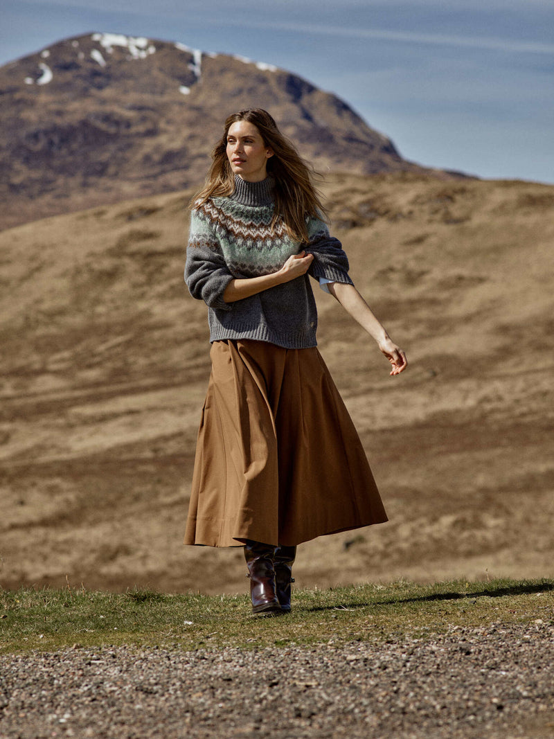Model wears the Mos Mosh Daya Fjord sweater featuring a jacquard brown and frosty green fair isle patter on grey from The SHOE GALLERY teamed with a brown skirt and boots