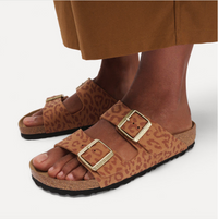 Pair of leopard print Birkenstock Arizona sandals with gold buckles worn by model