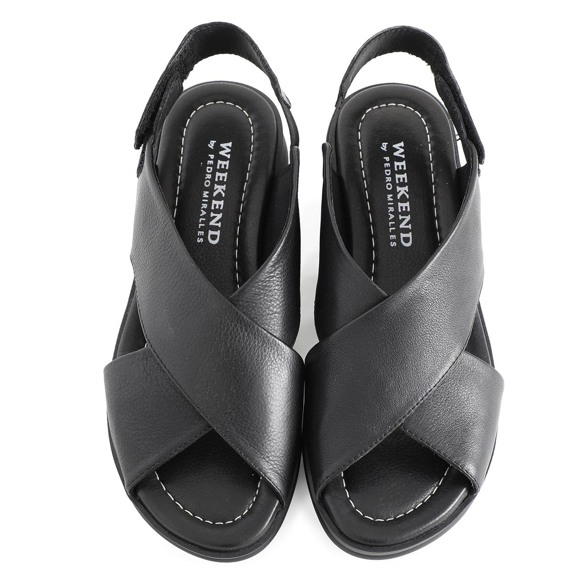soft leather open toe black sandals with back strap with velcro closure on a cushioned small platform sole. Overhead viewpoint.