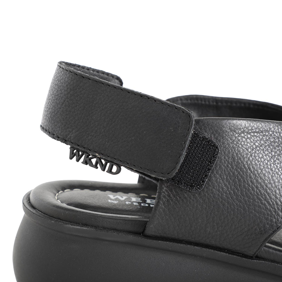 soft leather open toe black sandals with back strap with velcro closure on a cushioned small platform sole. Close up of fastening and branding