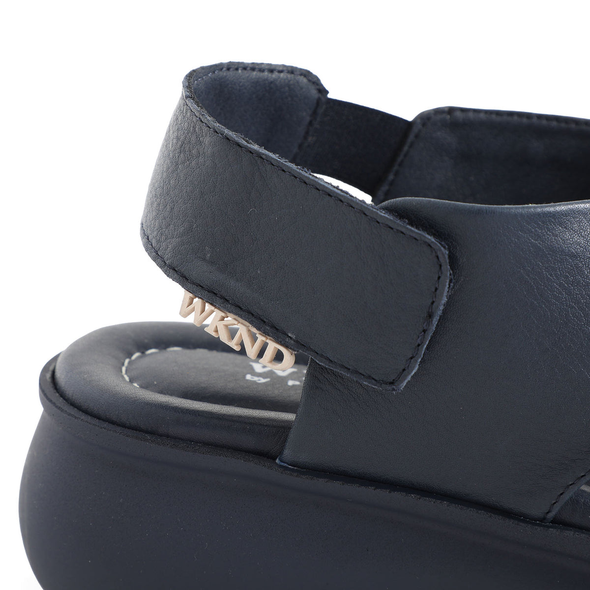 soft leather navy sandals with velcro fastening and cushioned navy slightly platformed sole. This image shows velcro closure and branding