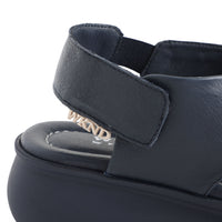 soft leather navy sandals with velcro fastening and cushioned navy slightly platformed sole. This image shows velcro closure and branding