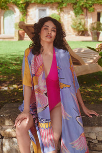 Model wears a One Hundred Stars Giant Crane Throwover in bright pinks and lilac over a swimsuit. Available at theshoegallery.co.uk