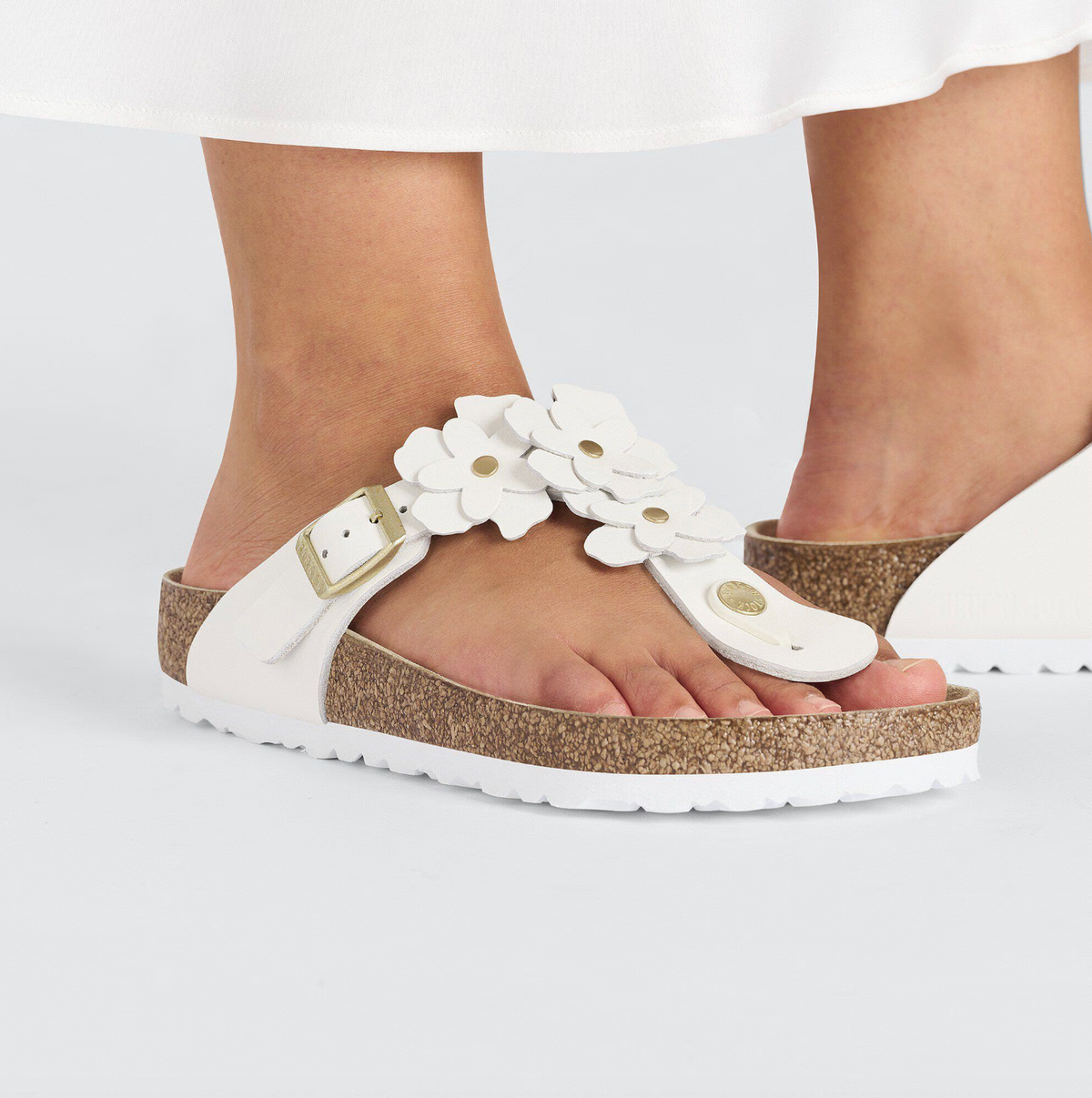 A pair of Birkenstock white leather flower embellished sandals with buckle closure