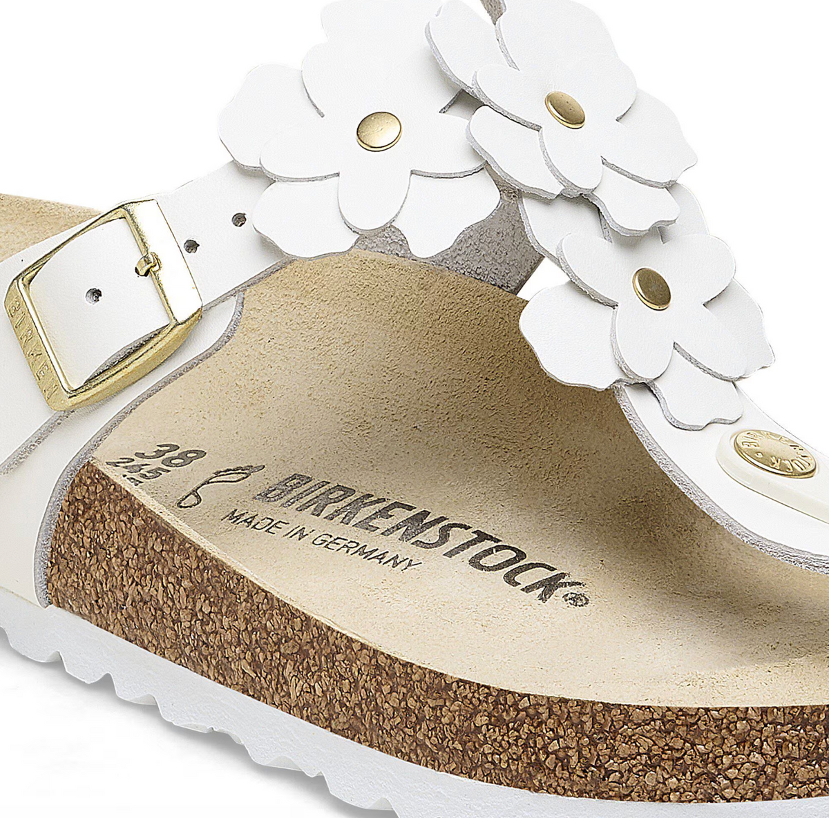 Close-up of a white sandal with floral details and 'Birkenstock' branding on a white background.