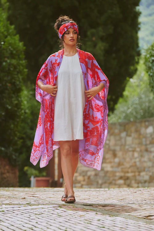 Model wears a One Hundred Stars Giant Willow Throwover in bright red and lilac over a white dress. Available at theshoegallery.co.uk