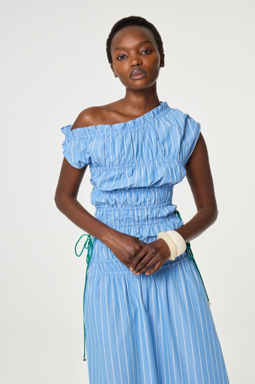 model is wearing a blue off-shoulder ruched top with green ties at the side. It is teamed with a matching Fabienne Chapot skirt
