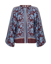 A long-sleeve Mos Mosh blouse with a maroon base and a light blue and white botanical block print pattern, featuring a split neckline 