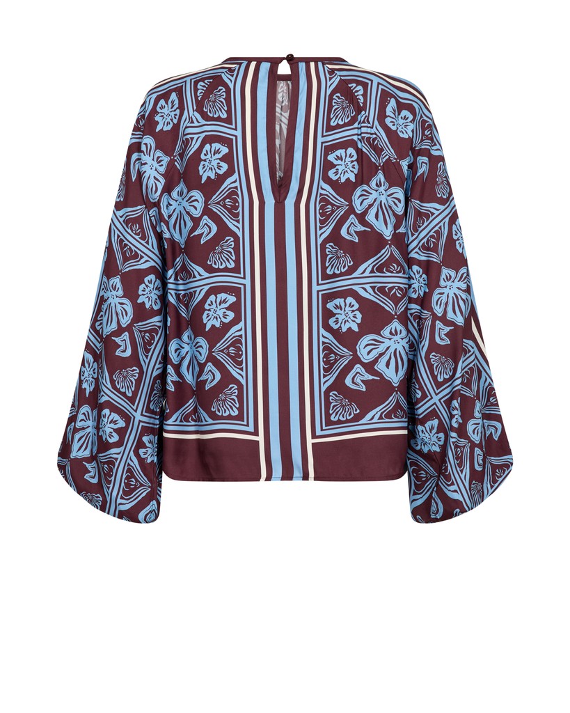 A long-sleeve Mos Mosh blouse with a maroon base and a light blue and white botanical block print pattern, featuring a split neckline 