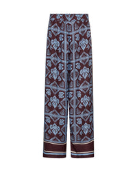 Mos Mosh wide-leg pants featuring a dark brown base with a light blue and white geometric and floral block print pattern, shown against a plain white background.