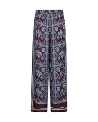 Mos Mosh wide-leg pants featuring a dark brown base with a light blue and white geometric and floral block print pattern, shown against a plain white background.