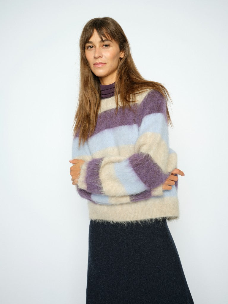 Model wears a striped Mos Mosh sweater in purple blue and beige