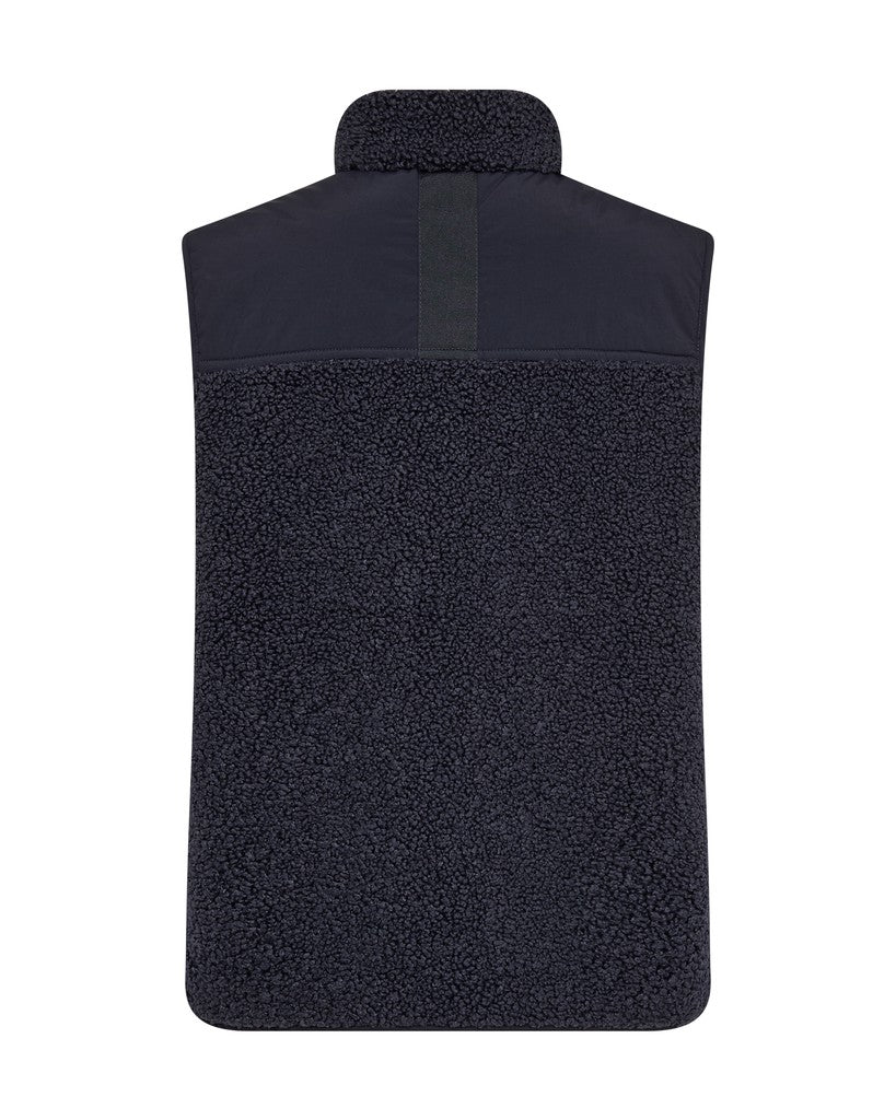 Model wears a dark navy Mos Mosh fleece vest with two way zip and zipped pocket - back view