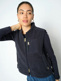 Model wears a dark navy Mos Mosh fleece vest with two way zip and zipped pocket over a matching long-sleeve top and blue jeans