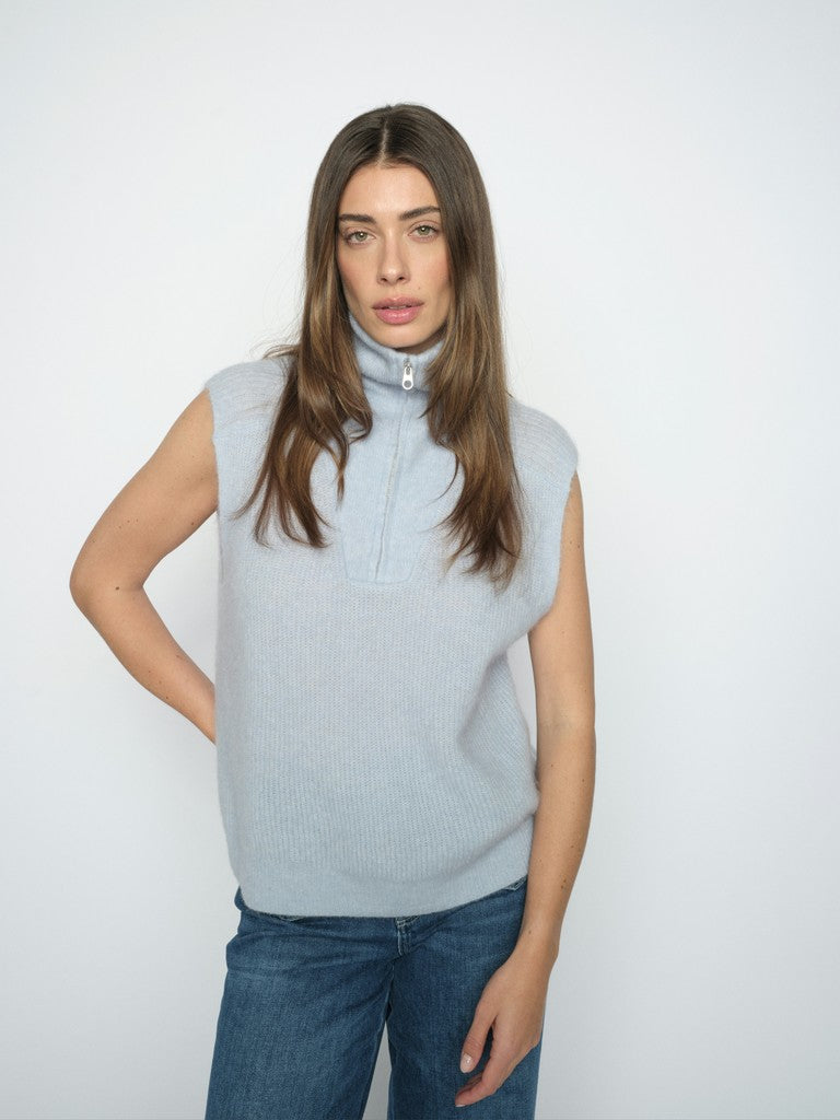 Model wears a pale blue Mos Mosh sleeveless sweater with zipped high neck 