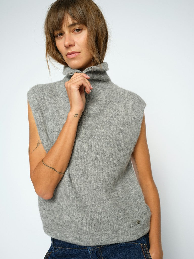 Model wears a light grey Mos Mosh ribbed knit sleeveless turtleneck sweater vest, paired with blue jeans