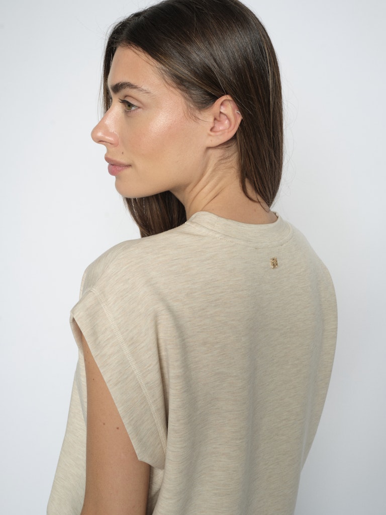 Model wears relaxed fit sleeveless beige sweatshirt