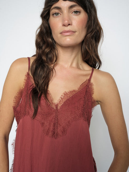 model wears a terracotta slip top dged with fine lace