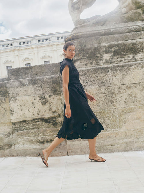 model wears a black maxi dress with ruched body and long skirt with lace detail