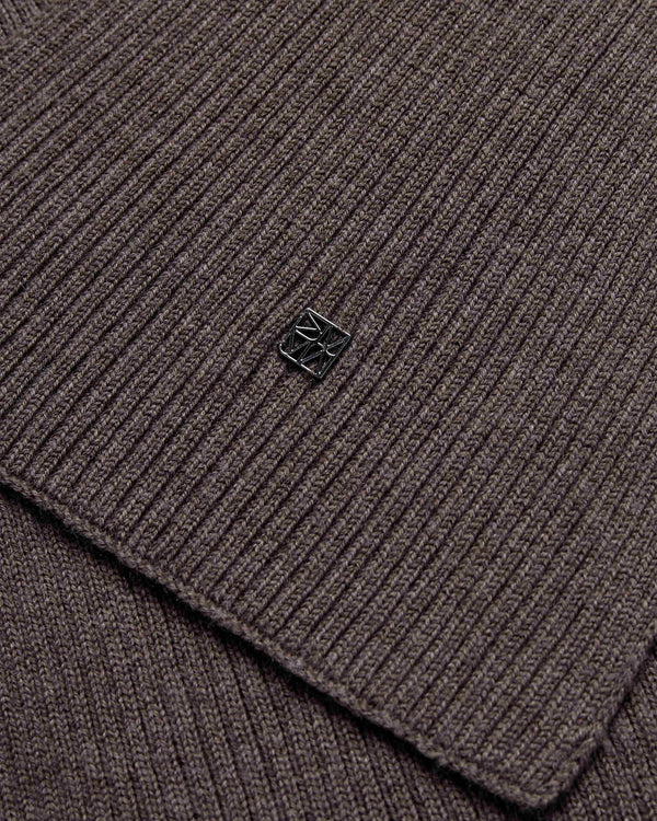 Close-up of the mole brown ribbed wool knit Mos Mosh Scarf with a small logo charm in the centre
