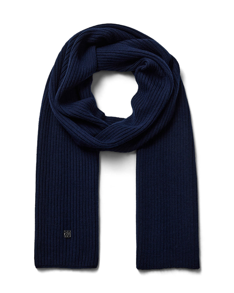 A dark navy blue ribbed Mos Mosh wool knit scarf, neatly folded and looped to display its texture and length, with a discreet logo on one end available at The Shoe Gallery