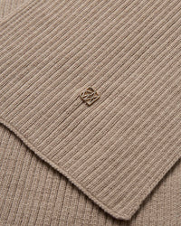 Close-up of the beige ribbed wool knit Mos Mosh Scarf with a small logo charm in the centre.