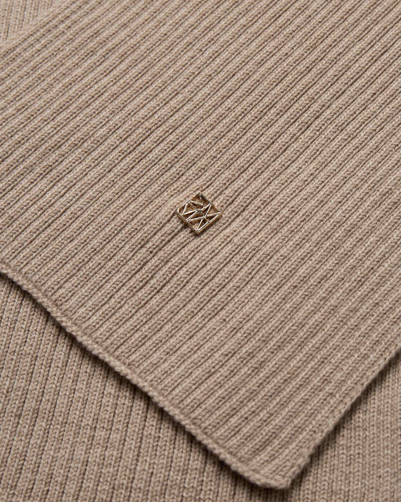 Close-up of the beige ribbed wool knit Mos Mosh Scarf with a small logo charm in the centre.