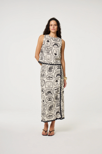 Models wears a wrap style skirt in black and white tile pattern edged with black rick rack by Fabienne Chapot
