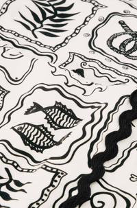 Models wears a wrap style skirt in black and white tile pattern edged with black rick rack by Fabienne Chapot, close up detail