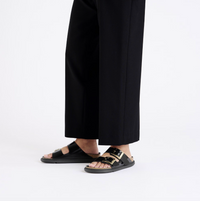 Model wearing Black Birkenstock Arizona sandals with gold buckles and black bumper style soles