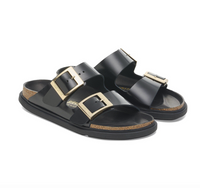 Black Birkenstock Arizona sandals with gold buckles and black bumper style soles