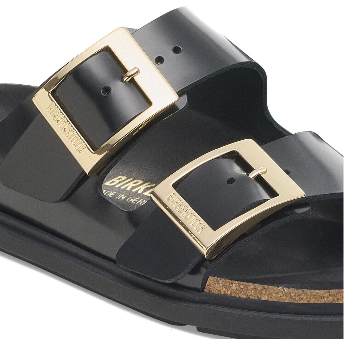 Black Birkenstock Arizona sandals with gold buckles and black bumper style soles, close up viewpoint