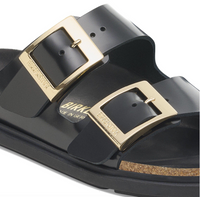 Black Birkenstock Arizona sandals with gold buckles and black bumper style soles, close up viewpoint