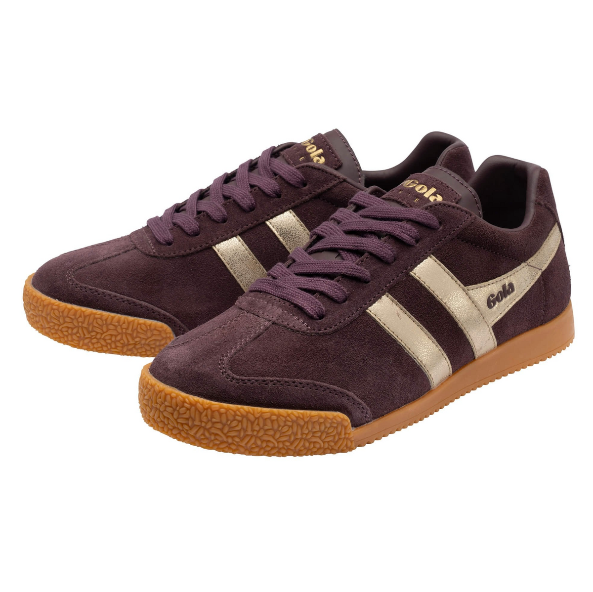 A pair of Gola Harrier low-top sneakers in dark brown  plumb suede with gold side stripes, tonal laces, and a textured gum sole, available at The SHOE GALLERY