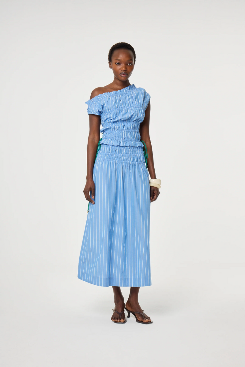 model is wearing a blue off-shoulder ruched top with green ties at the side. It is teamed with a matching Fabienne Chapot skirt