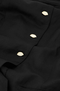 close up of black round necked Fabienne Chapot waistcoat with small cream buttons