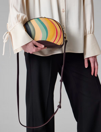 A Paul Smith dusky swirl  striped bag in a camera bag style. Centre gold coloured zip and deep burgundy across body strap, available at The Shoe  Gallery