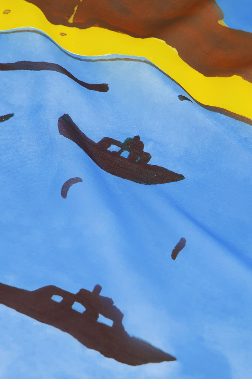 Fabienne Chapot large scarf featuring a painting of a coastal scene with boats, a lighthouse, and mountains, close up detail