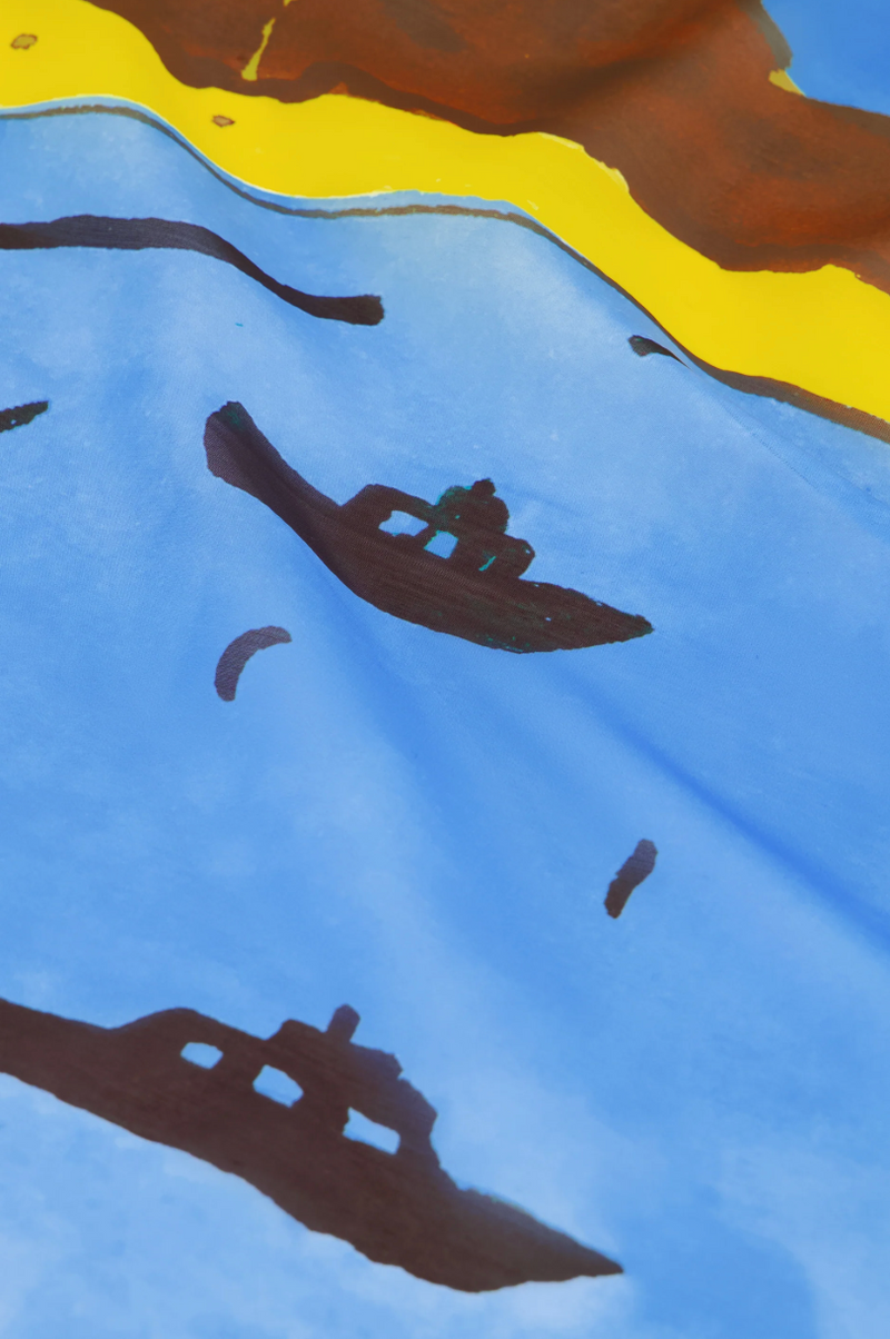 Fabienne Chapot large scarf featuring a painting of a coastal scene with boats, a lighthouse, and mountains, close up detail
