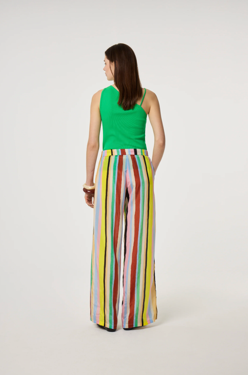 Model is wearing a green top and colorful Fabienne Chapot striped pants, back view