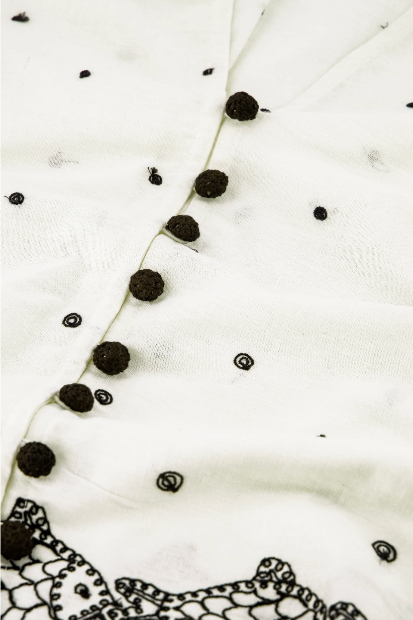 close up detail showing fabric and small black buttons and embroidered detail