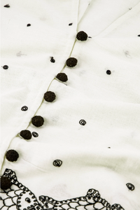 close up detail showing fabric and small black buttons and embroidered detail