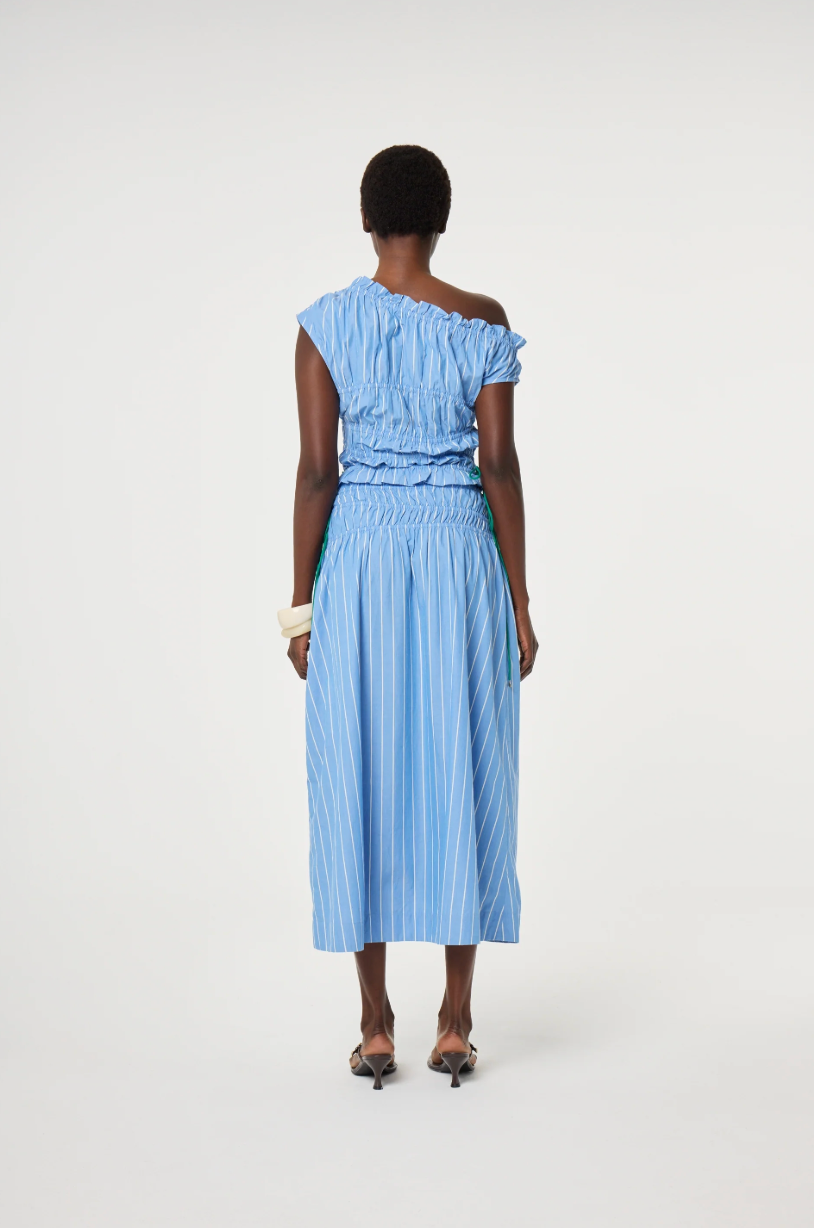Model wears a blue off-shoulder top and skirt in 100% cotton with ruching detail by Fabienne Chapot, back view