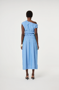Model wears a blue off-shoulder top and skirt in 100% cotton with ruching detail by Fabienne Chapot, back view