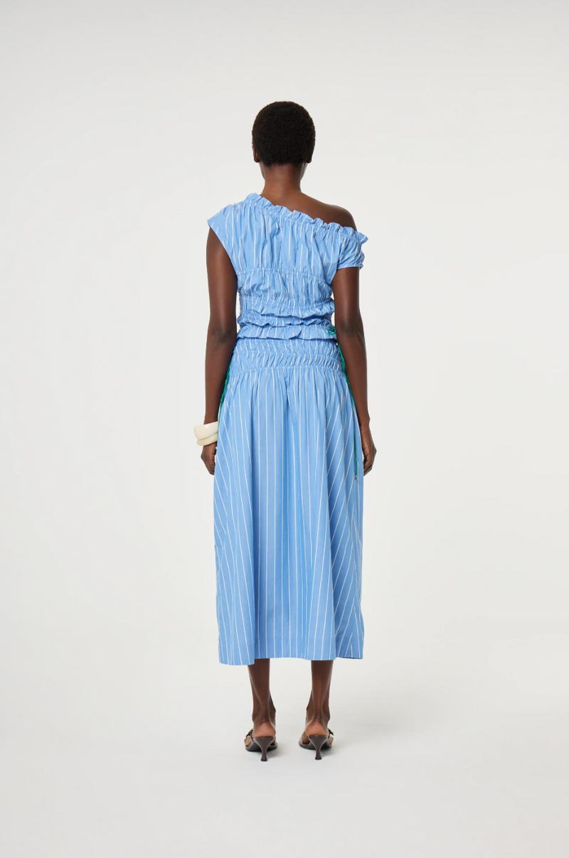 Model wears a blue off-shoulder top and skirt in 100% cotton with ruching detail by Fabienne Chapot, back view